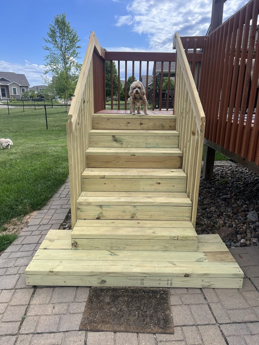 Rebuilt deck stairs front view from the yard, pergola behind